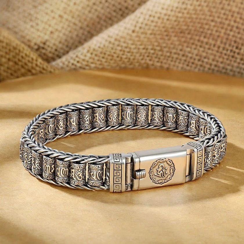 Handcrafted Buddhist mantra copper bracelet top-down flat lay on burlap fabric background, showing vintage patina and engraved OM clasp detail