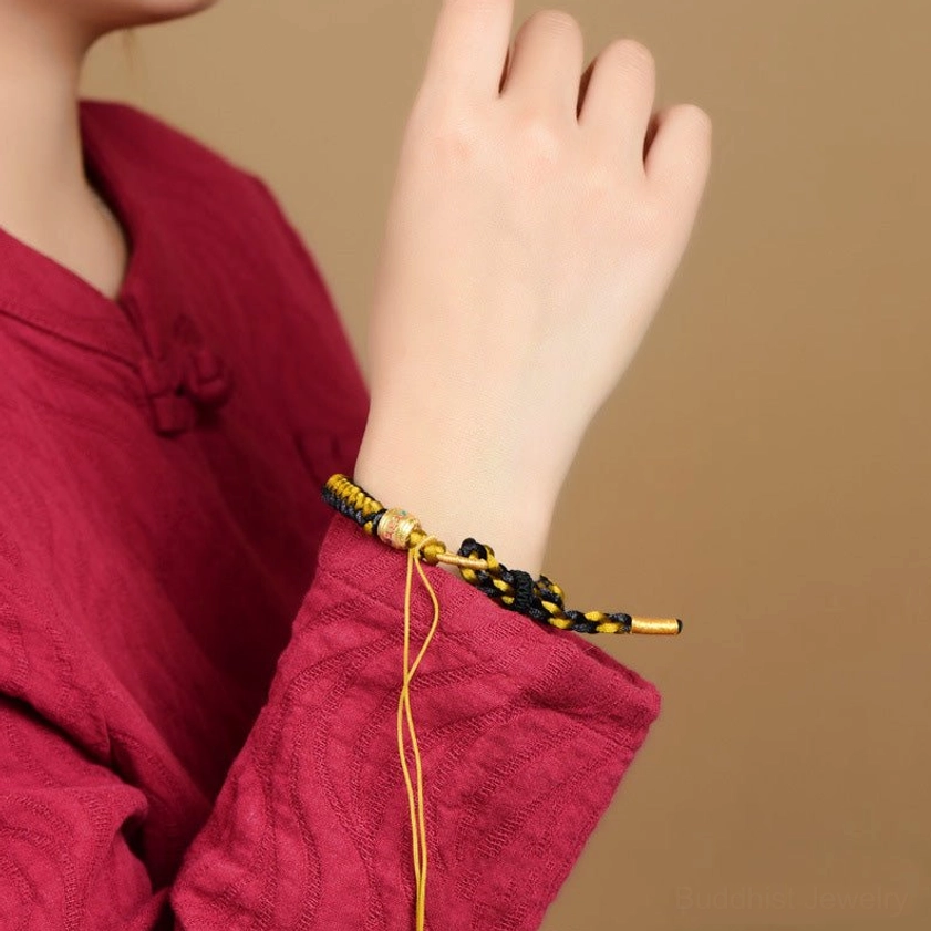 Wrist wearing demonstration of adjustable dragon scale bracelet with Om Mani Padme Hum mantra on person in red traditional clothing