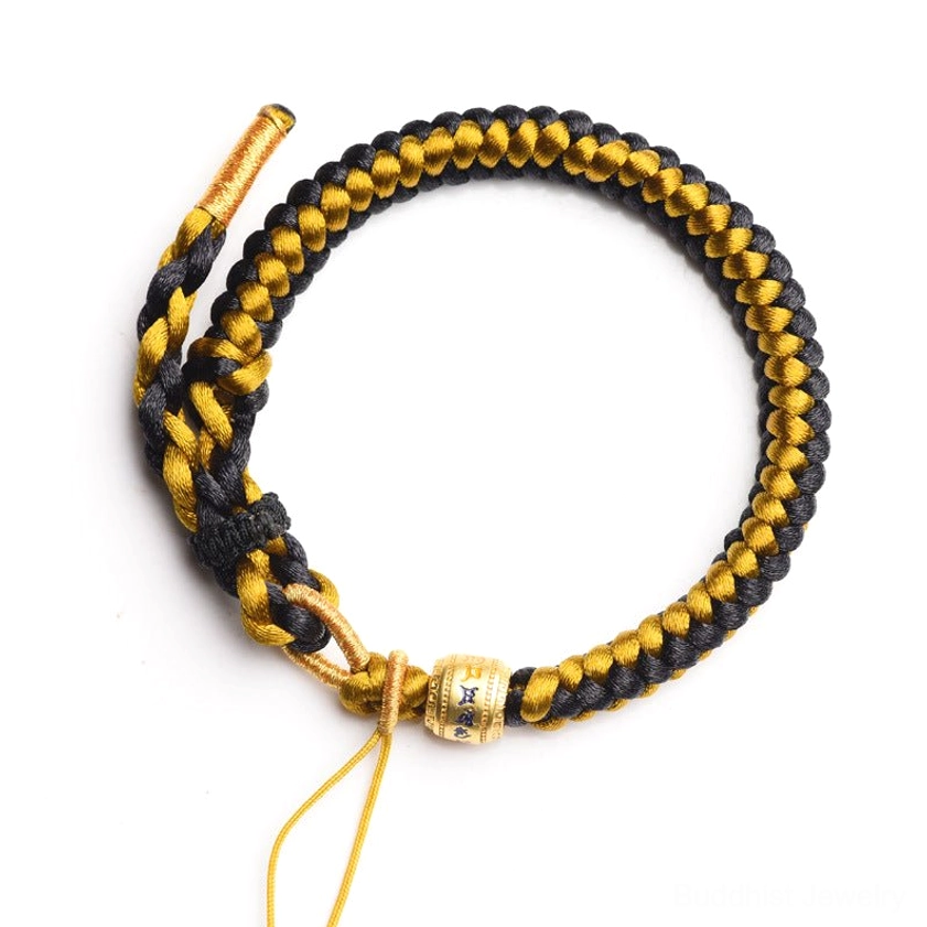 Handmade black and gold Om Mani Padme Hum spiritual bracelet with engraved mantra bead on brown craft paper