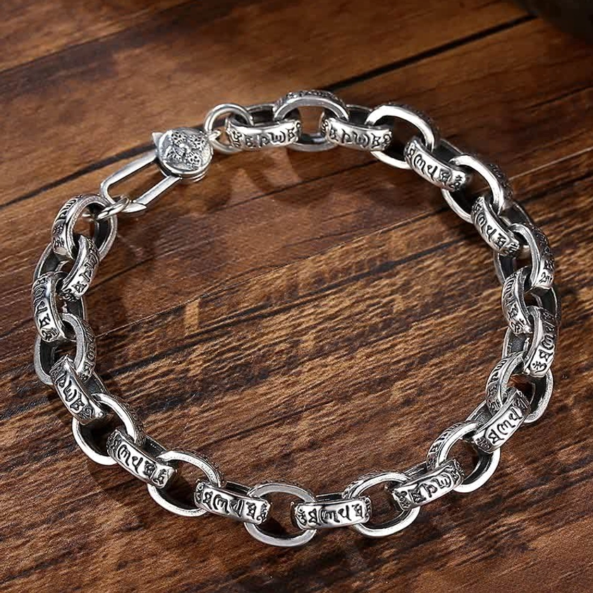 Close-up detail of 925 sterling silver Om Mani Padme Hum engraved chain links with studded clasp on dark wooden surface