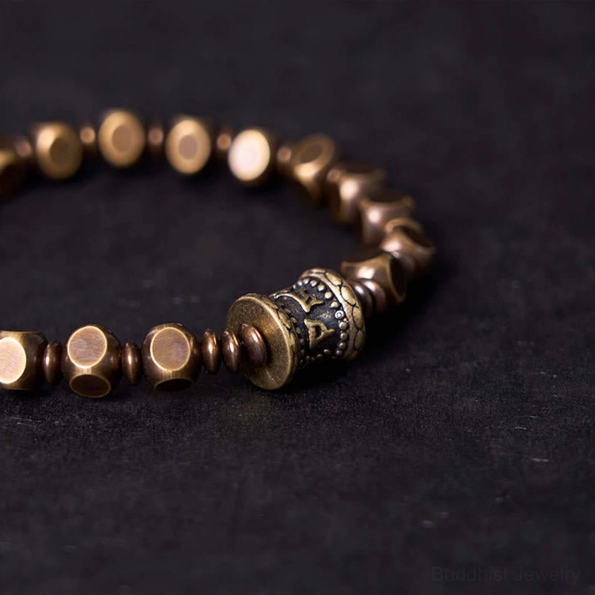 Close-up detail of carved Om Mani Padme Hum center bead on brass bracelet