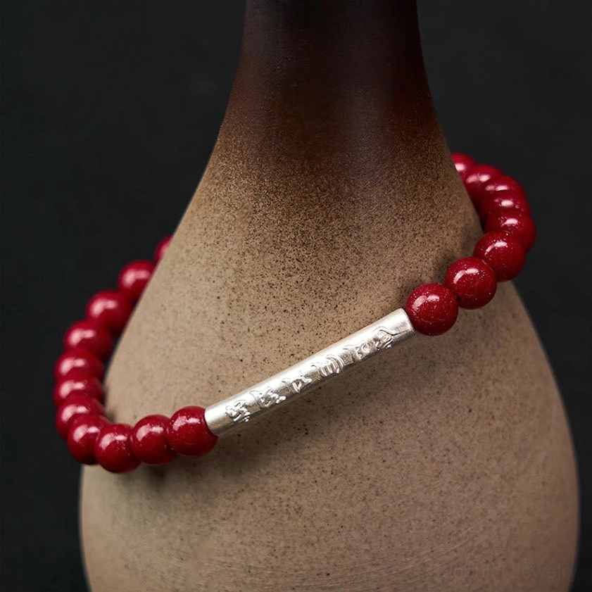 Om Mani Padme Hum cinnabar and gold accent bracelet variation, showing rich red beads with warm-toned engraved metal tube
