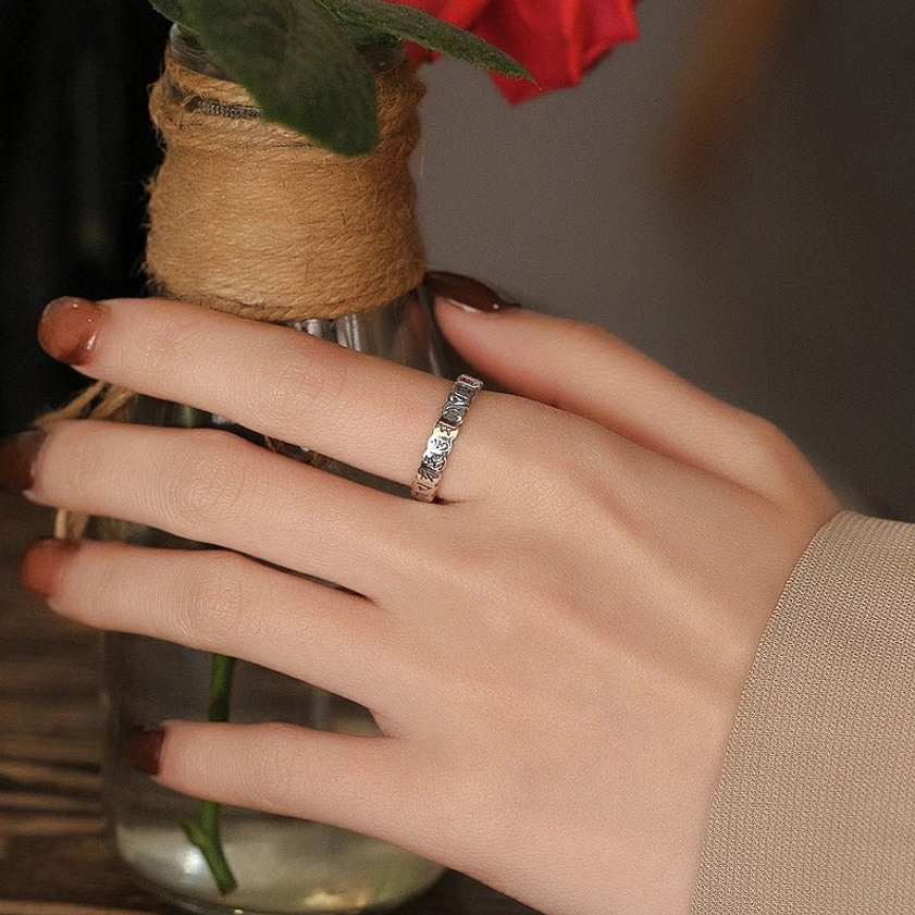 Adjustable Om Mani Padme Hum ring worn on hand - lifestyle photography with beige sleeve and flower vase decoration