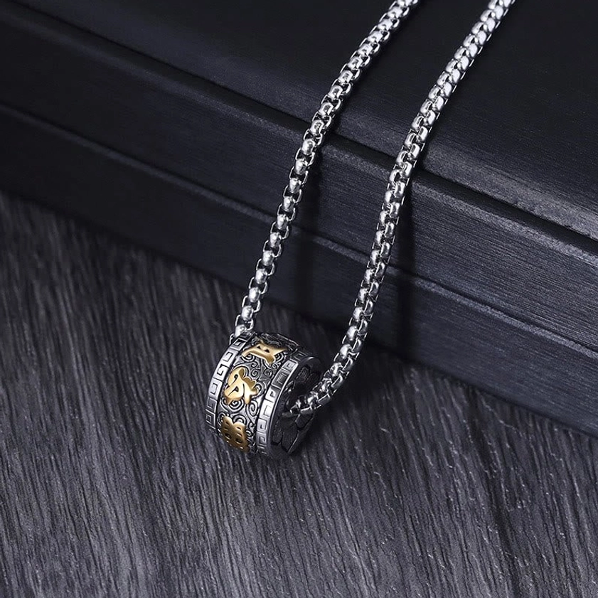 All-silver Om Mani Padme Hum necklace with wheat link chain, side view on wooden table with black display box