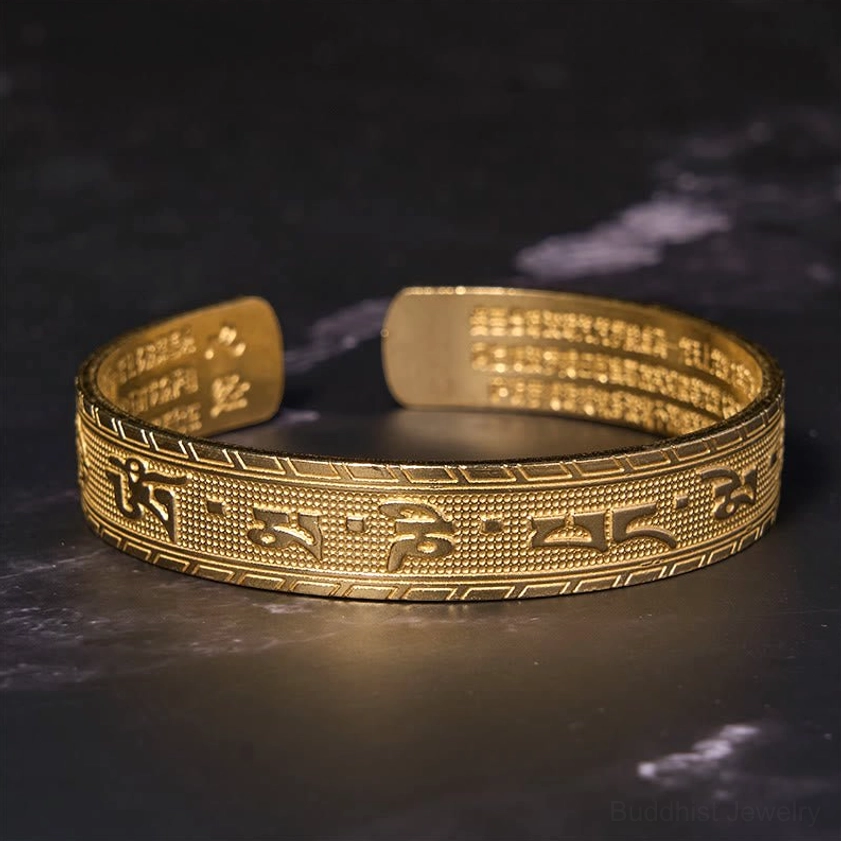 Direct overhead shot of adjustable open cuff mantra bracelet with brass finish displaying engraved Om Mani Padme Hum on outer and inner band surfaces