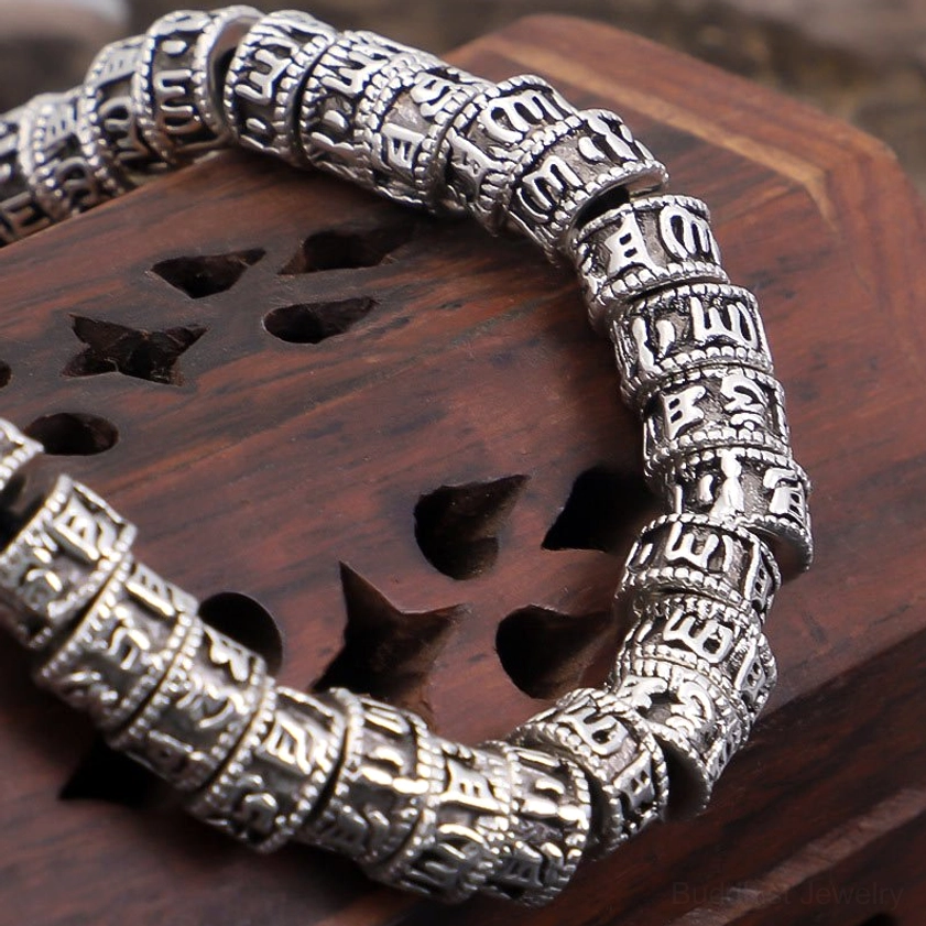 Close-up macro view of engraved Tibetan Buddhist script on cylindrical mantra beads