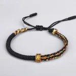 Om Mani Padme Hum black Buddhist string bracelet with colorful chakra-inspired braided accents and copper mantra bead flat lay photography