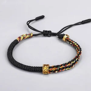 Om Mani Padme Hum black Buddhist string bracelet with colorful chakra-inspired braided accents and copper mantra bead flat lay photography