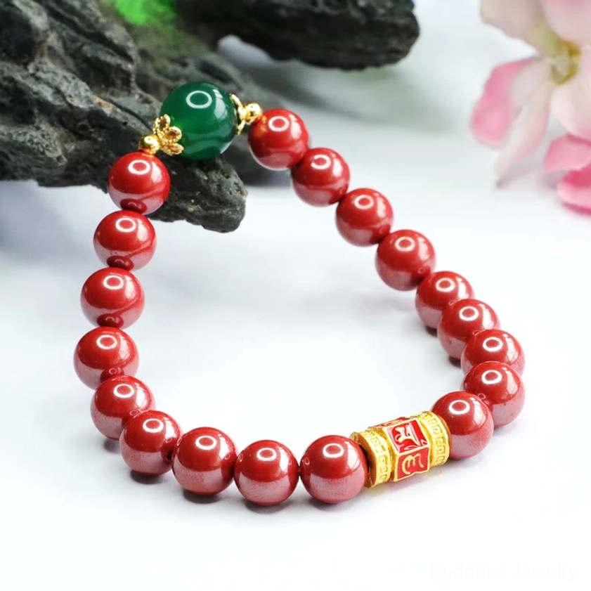 Sacred Om Mani Padme Hum blessing bracelet with natural red cinnabar beads and green stone accent angled display
