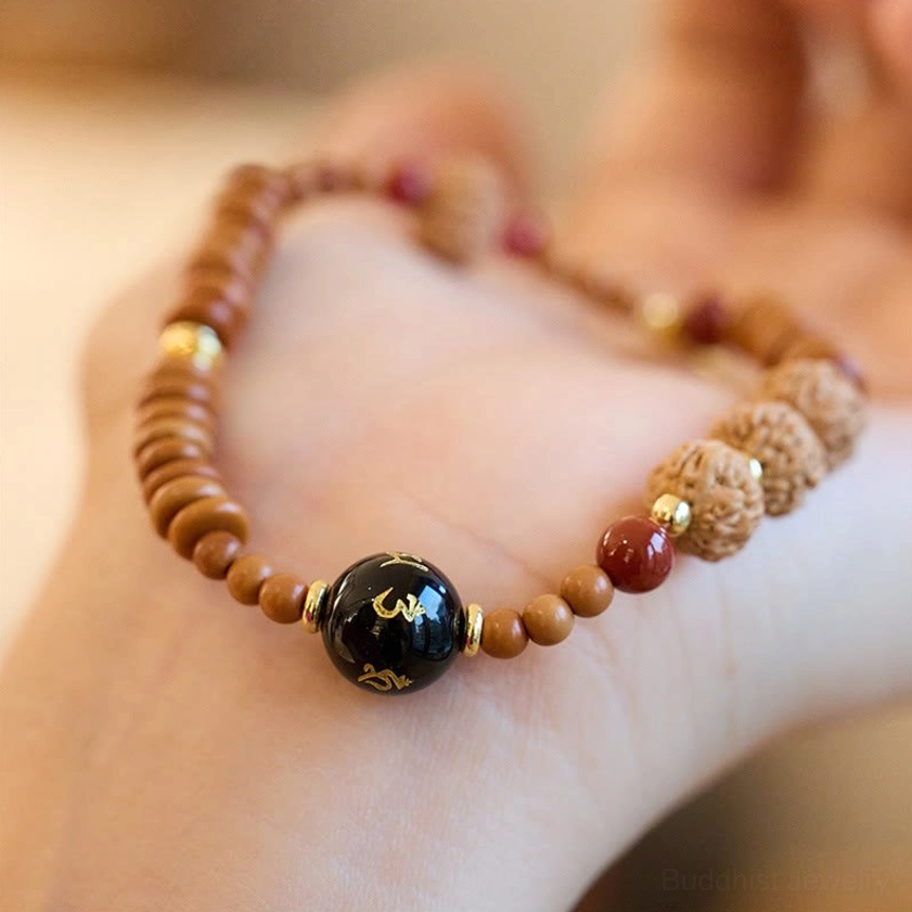 Om Mani Padme Hum Buddhist bracelet with engraved black onyx bead held in hand side view