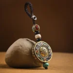 Om Mani Padme Hum Bodhi seed keychain with brass pendant and colorful enamel inlays, displayed on vintage desktop