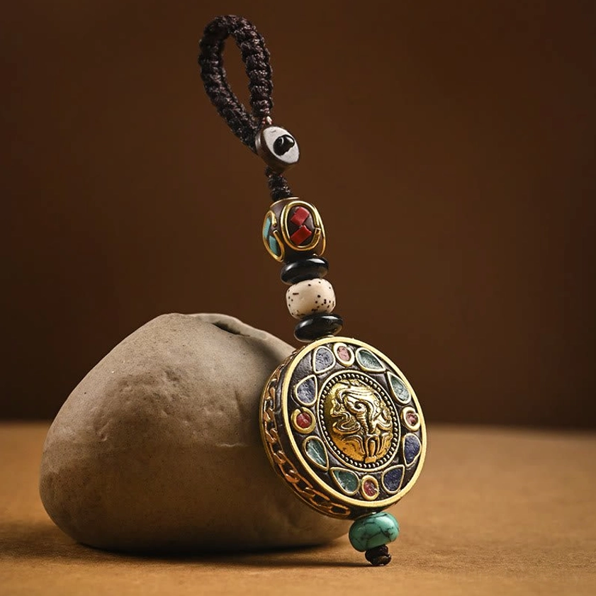 Om Mani Padme Hum Bodhi seed keychain with brass pendant and colorful enamel inlays, displayed on vintage desktop