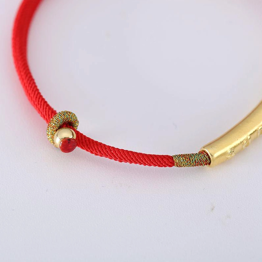 Om Mani Padme Hum red string bracelet with gold tube and red bead decoration on white background