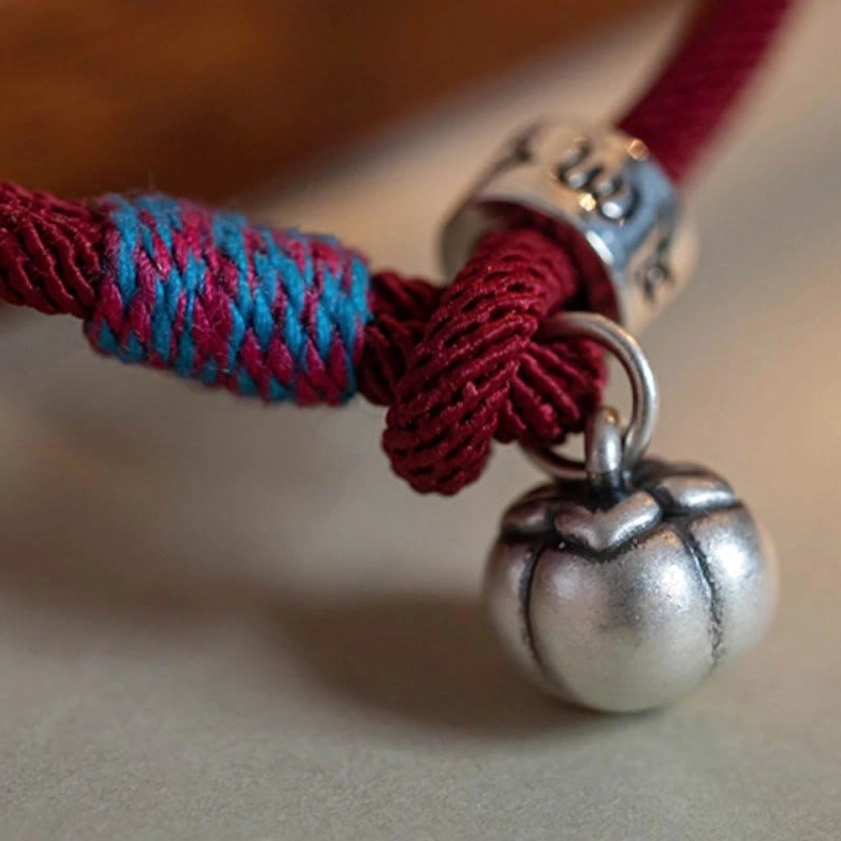 Detailed macro photography of Om Mani Padme Hum bracelet charms and colorful woven decorative knot