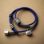 Om Mani Padme Hum carved bracelet with dark blue braided rope and silver beads, flat lay top view