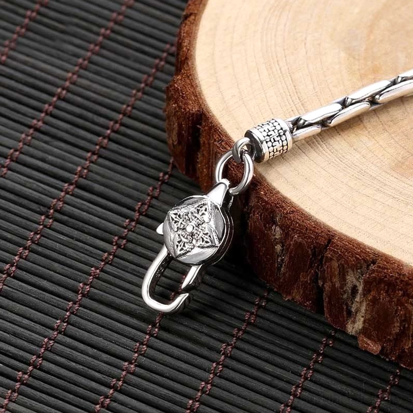 Sacred Buddhist bracelet clasp side view close-up showing carved silver details and linked chain texture