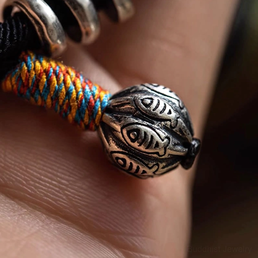 Carved fish-patterned silver pendant charm with colorful woven wrap on Buddhist bracelet