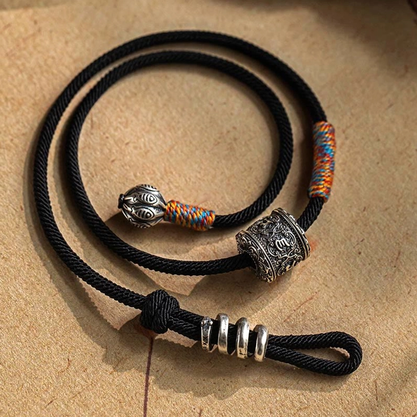 Buddhist mantra bracelet with fish-carved silver pendant and colorful woven textile detail on vintage kraft paper
