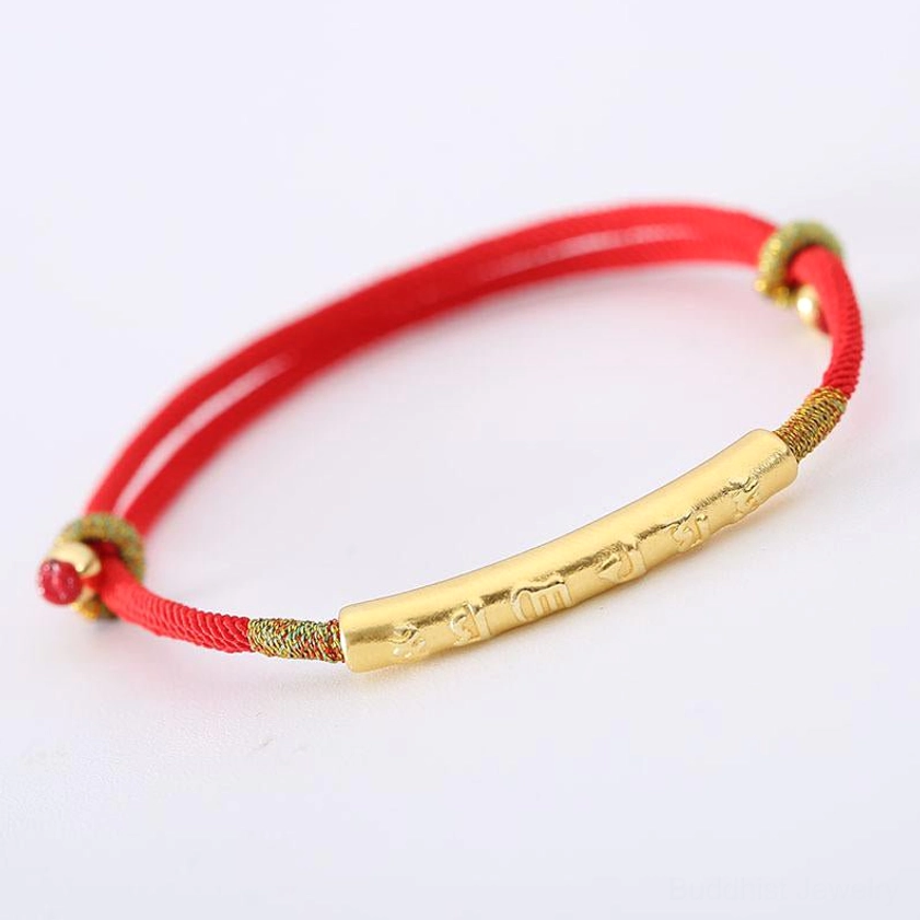 Om Mani Padme Hum red string bracelet with gold engraved tube and woven bead knot on white background
