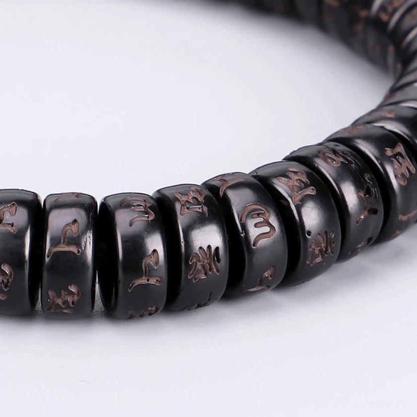 Full circular Om Mani Padme Hum coconut shell bracelet overhead view on white background