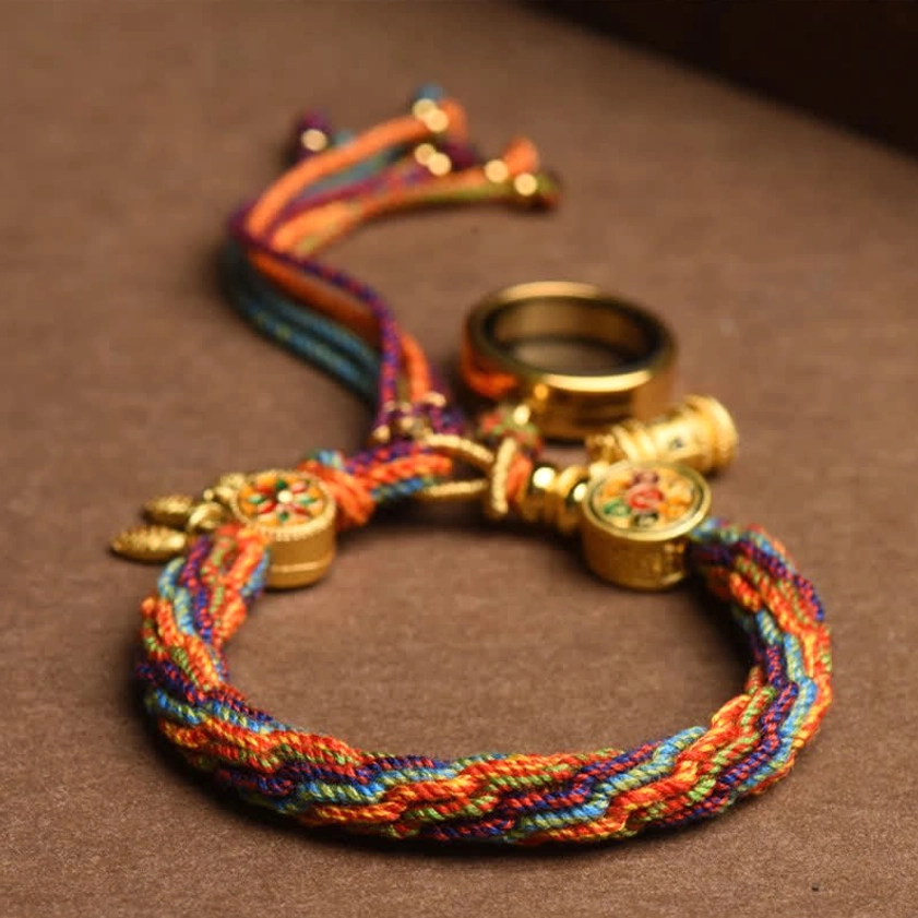 Multicolor woven Buddhist protection bracelet with gold metal clasps and emblems on wooden surface