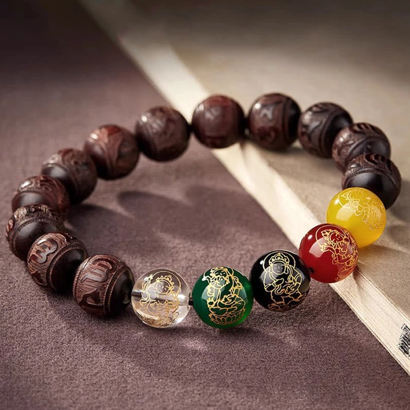 Om Mani Padme Hum red sandalwood bracelet with golden-patterned multicolored accent beads on wooden surface