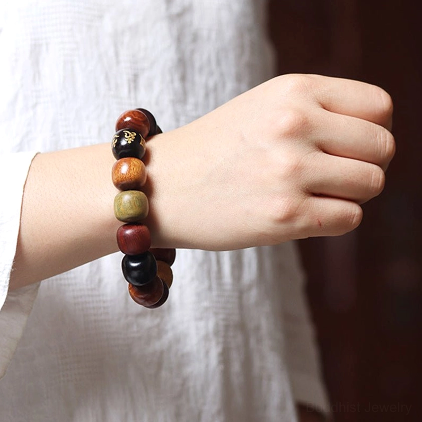 Hand-worn view of multi-wood Om Mani Padme Hum bracelet on side angle, displaying compact bracelet fit and natural wood bead variations