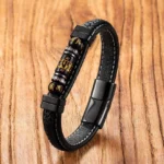Om Mani Padme Hum leather bracelet with black titanium steel clasp and engraved mantra beads, shot from overhead perspective on wooden background