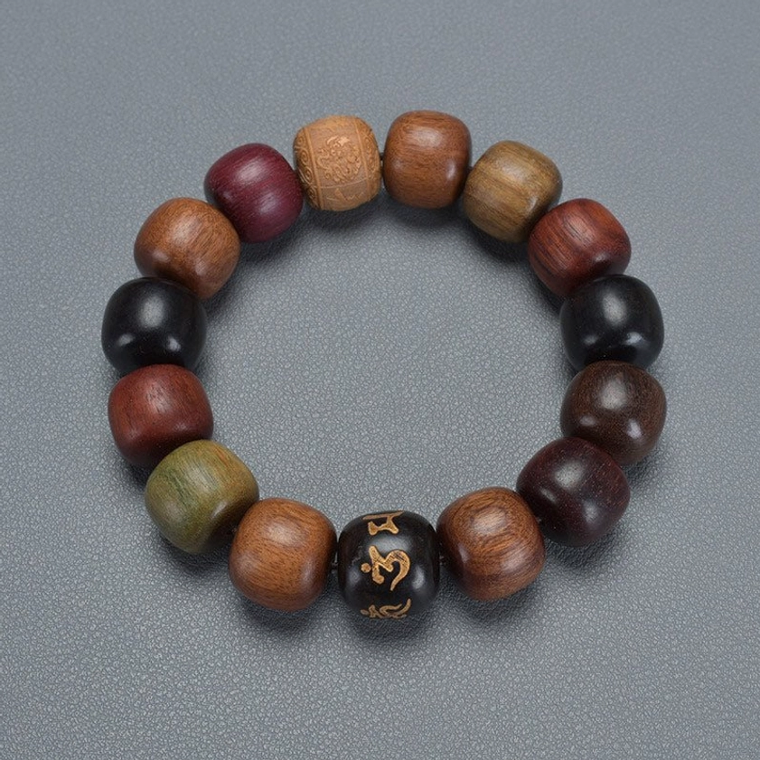 Top-down overhead shot of Om Mani Padme Hum Buddhist bracelet on gray background, uniform barrel-shaped wooden beads with golden mantra accent