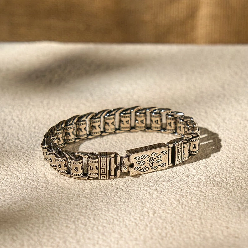 Overhead flat lay of Om Mani Padme Hum copper bracelet on neutral fabric showing full engraved band design