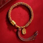 Handmade Om Mani Padme Hum multicolor braided bracelet with Ruyi charm on red velvet, flat lay top view