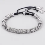 Handmade Om Mani Padme Hum mantra bracelet with engraved silver alloy beads and black cord, side oblique view