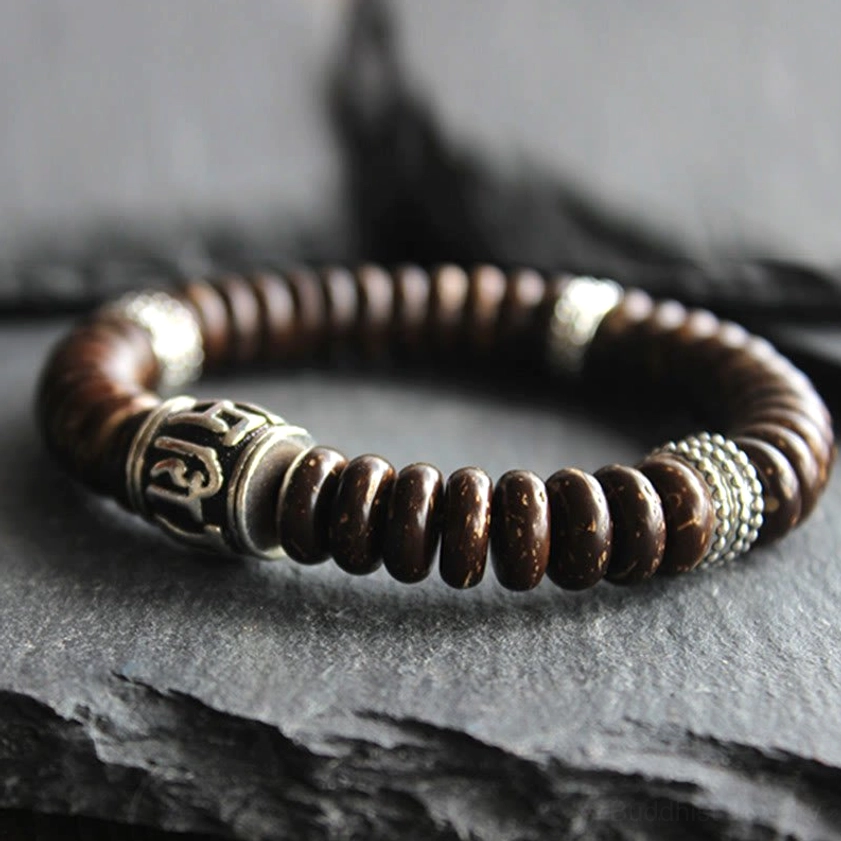 Three-quarter view of coconut shell Buddhist bracelet with engraved Sanskrit characters and silver spacer rings