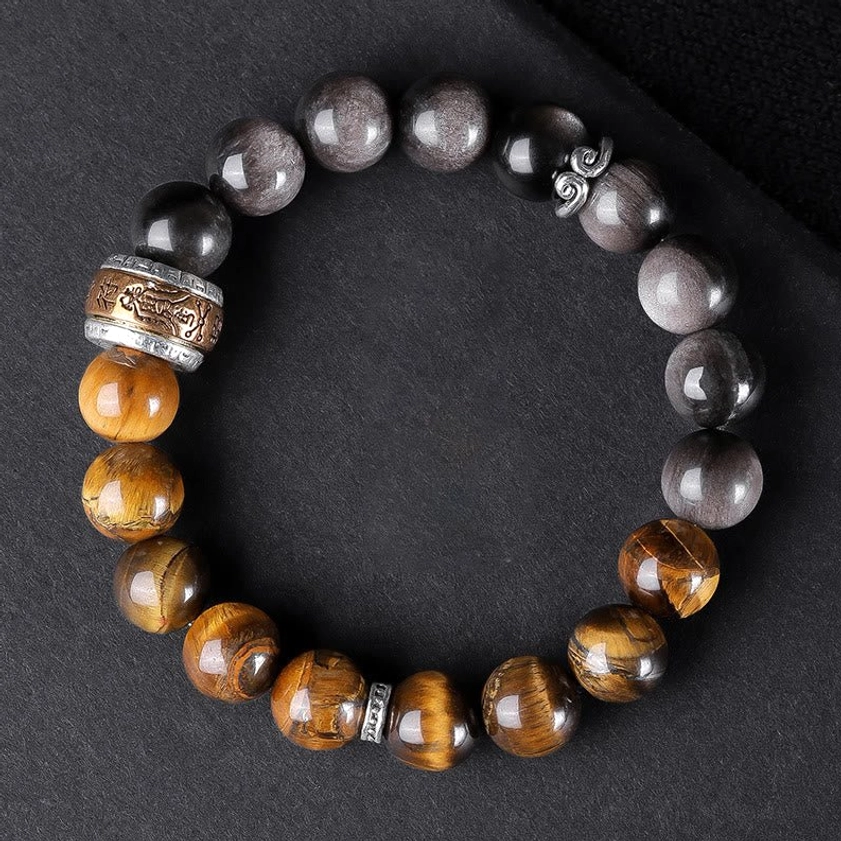 Dual-stone Buddhist beaded bracelet with Silver Sheen Obsidian and Tiger's Eye on black background, featuring engraved metal ring accessory and sacred symbol charm