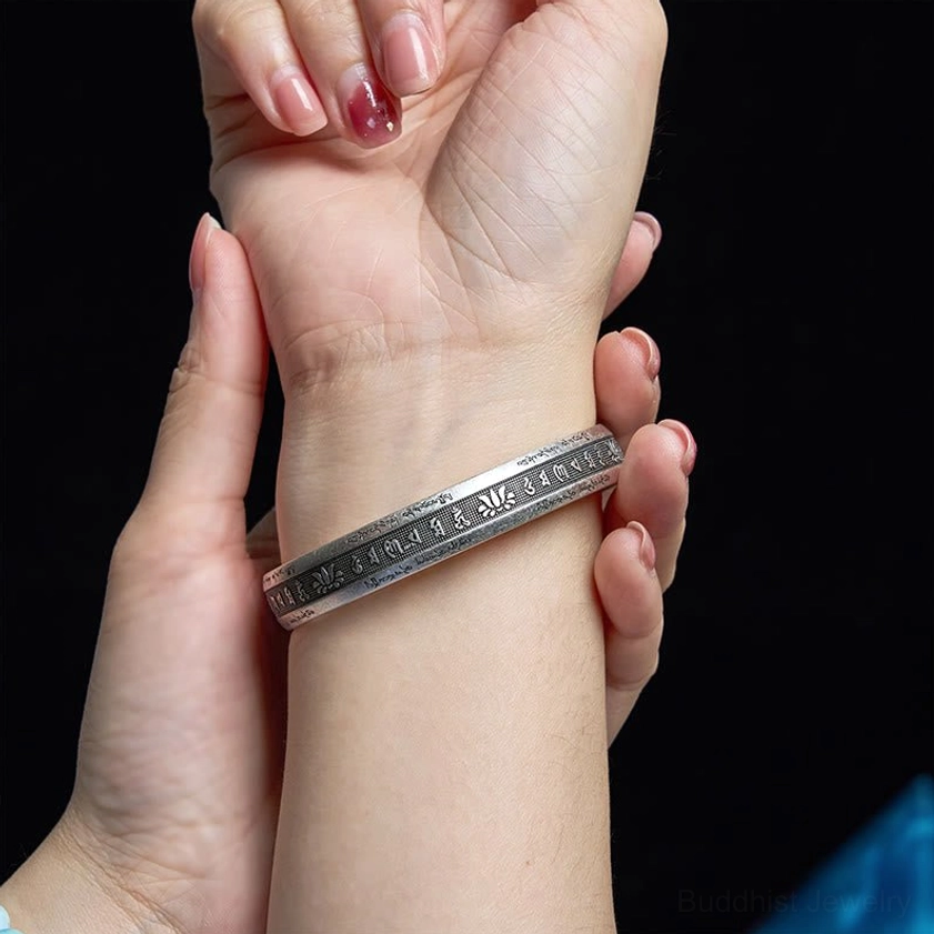 Buddhist cuff bracelet worn on wrist showing subtle engraved mantra details and matte silver finish