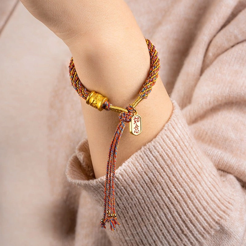 Multicolor Buddhist string bracelet worn on wrist with Om Mani Padme Hum charm and tassel detail