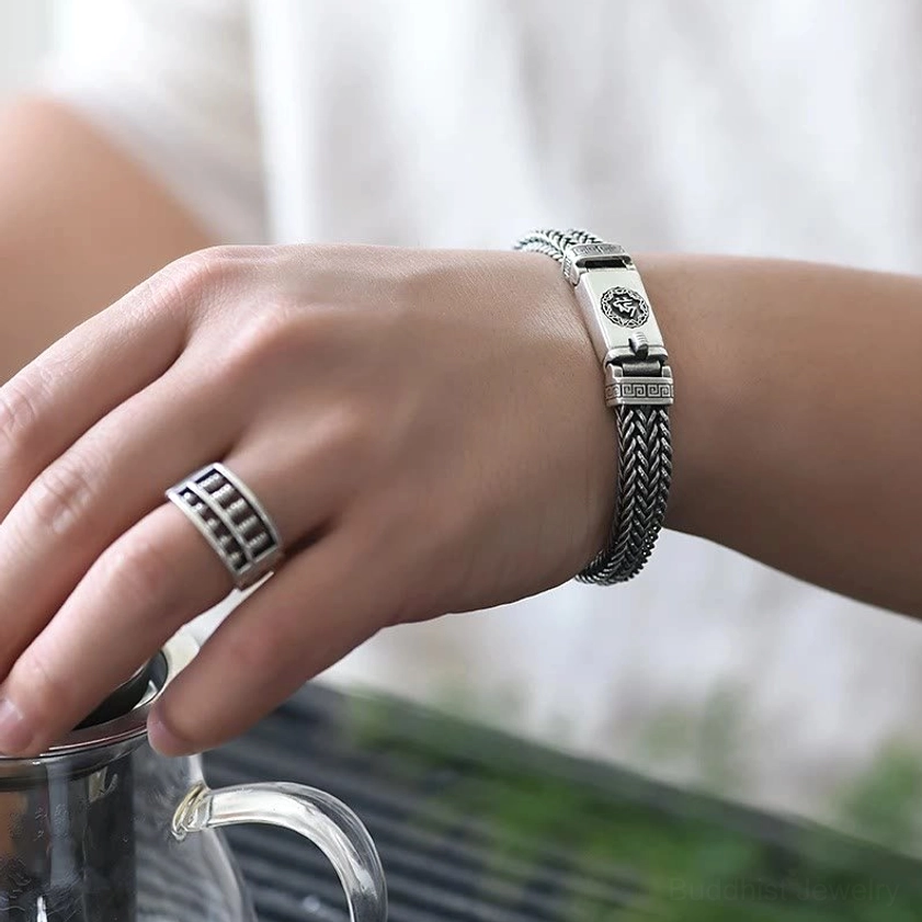 Wrist-worn braided copper Buddhist bracelet paired with matching ornamental ring in outdoor natural setting, real-life wear demonstration