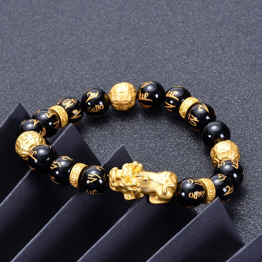 Om Mani Padme Hum mantra bracelet with clearly visible golden engravings on black beads and large gold Pi Xiu centerpiece
