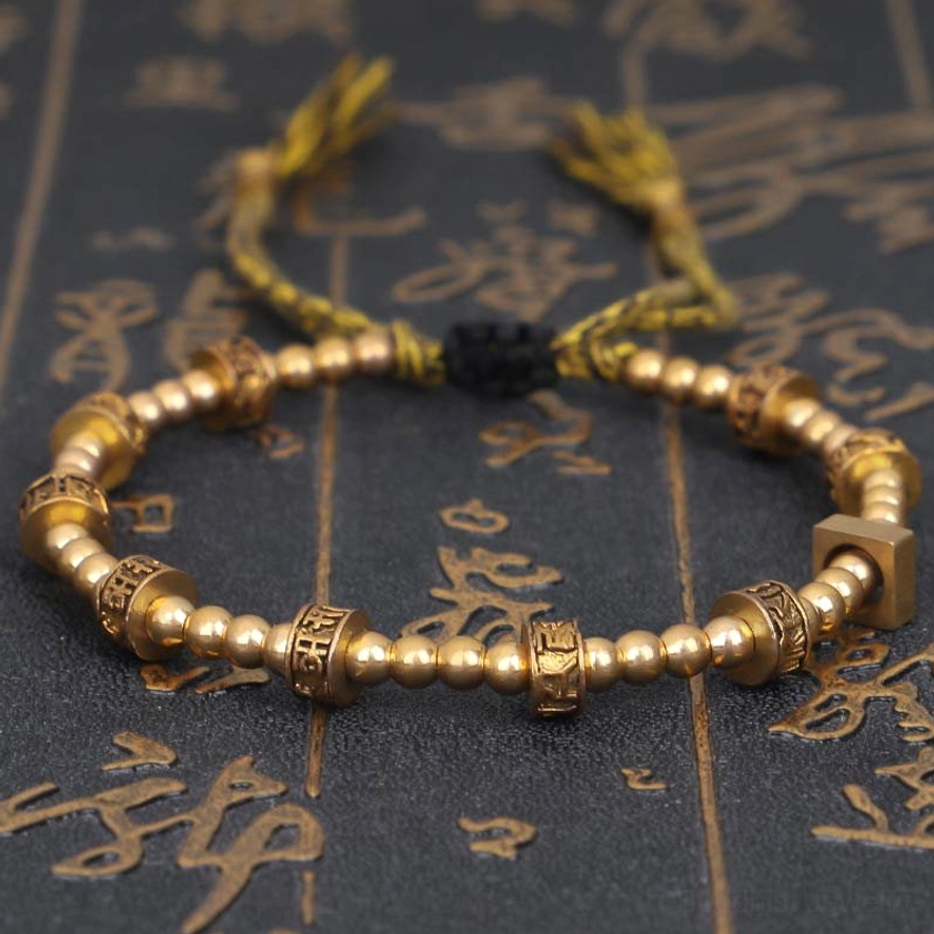 Om Mani Padme Hum Buddhist bracelet with bronze carved beads and beige stone accents on traditional calligraphy background