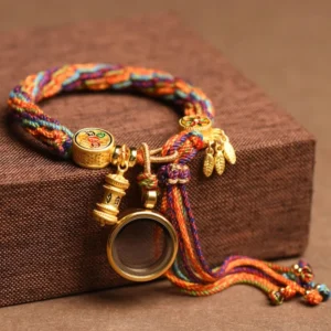 Om Mani Padme Hum Buddhist lucky string bracelet with multicolor braided cord and gold metal charms displayed on wooden box