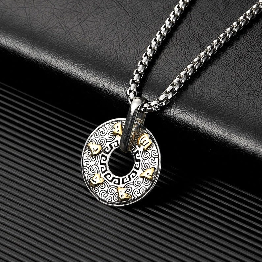 Om Mani Padme Hum Buddhist pendant necklace side angle close-up view on black striped leather background, featuring polished metal bail and detailed engraved mantra face
