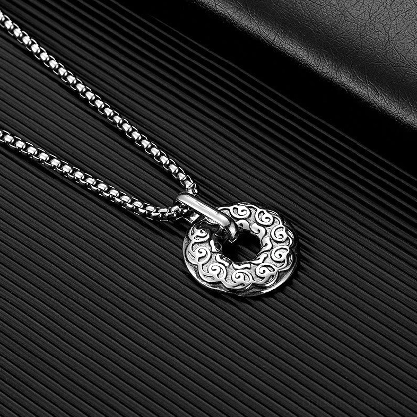 Silver Om Mani Padme Hum Buddhist donut pendant necklace side close-up showing cloud pattern engravings and no gold decoration on black striped leather backdrop