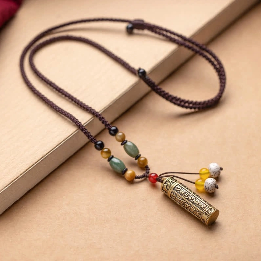 Om Mani Padme Hum Buddhist necklace worn on wearer with pendant resting at collarbone against red clothing