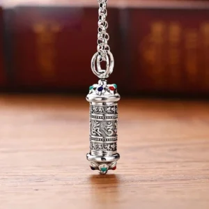 Om Mani Padme Hum silver Buddhist pendant necklace with engraved mantra and gemstone accents, front view on wooden surface