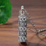 Om Mani Padme Hum Buddhist pendant necklace with twisted silver chain and swastika symbol, antique silver finish on wooden surface with green leaf