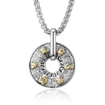 Om Mani Padme Hum Buddhist pendant necklace with silver and gold two-tone finish, close-up overhead view showing intricate mantra engraving and cloud pattern details on white reflective background