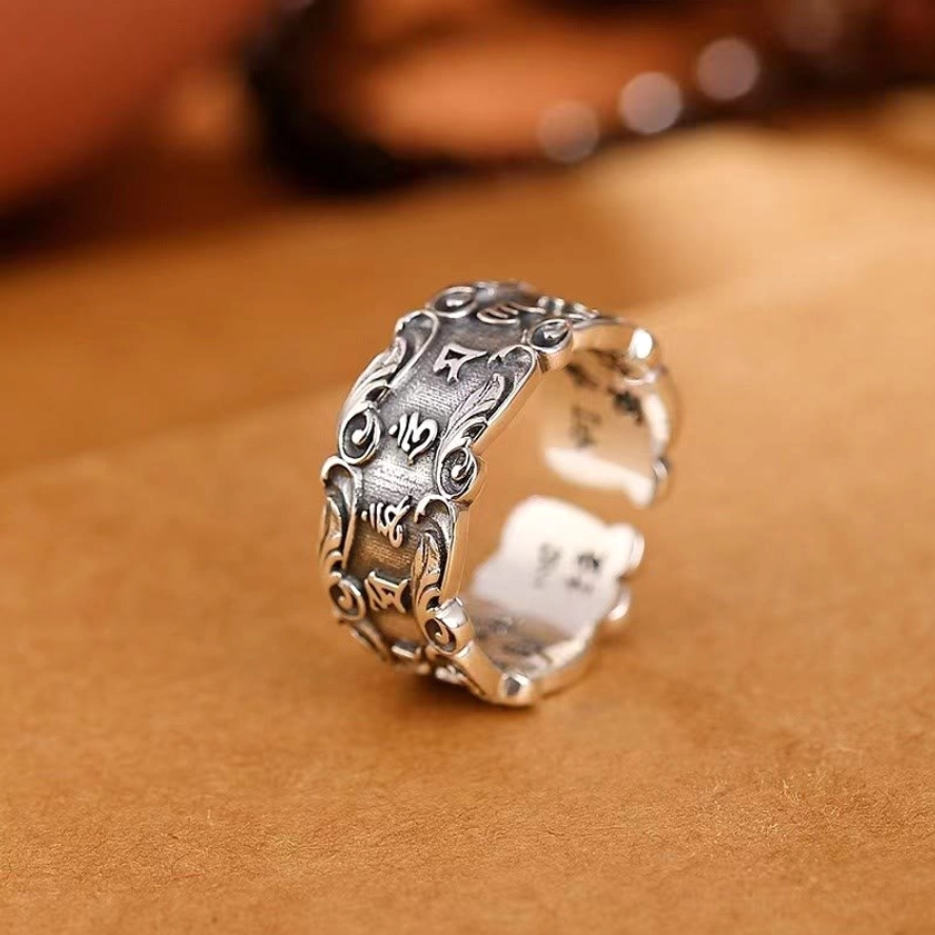 Om Mani Padme Hum Buddhist mantra ring silver left three-quarter view with carved Sanskrit mantras and decorative scroll borders on suede leather