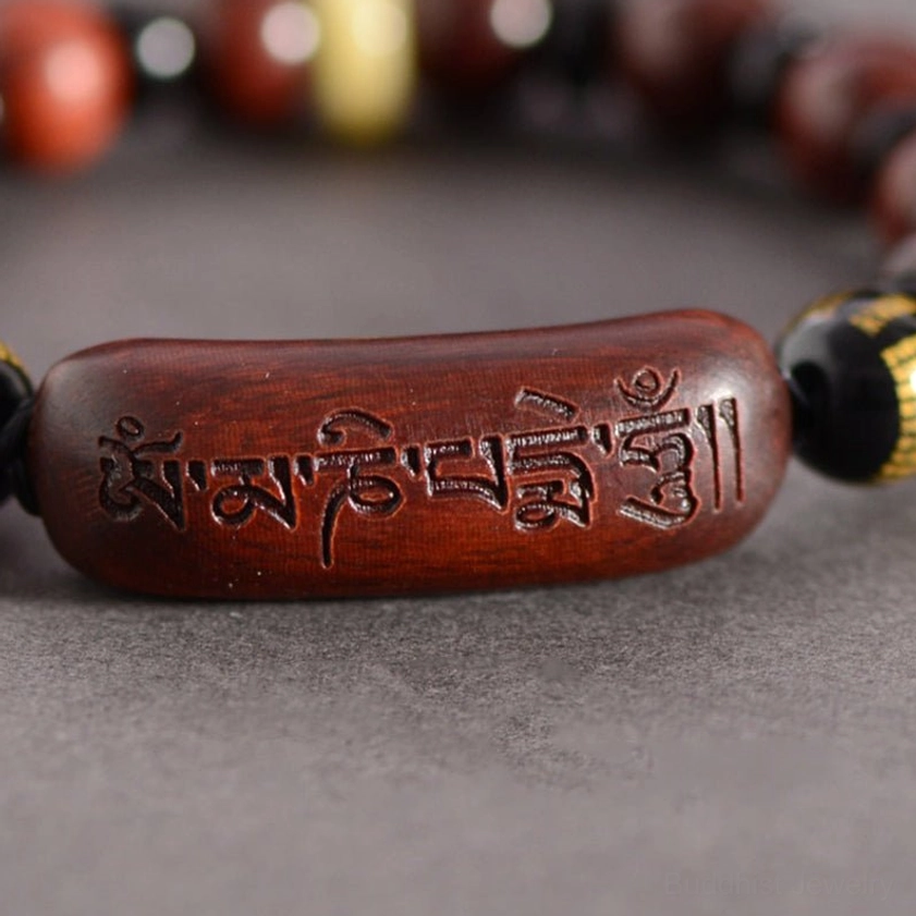 Macro close-up of engraved Om Mani Padme Hum mantra on sandalwood focal bead