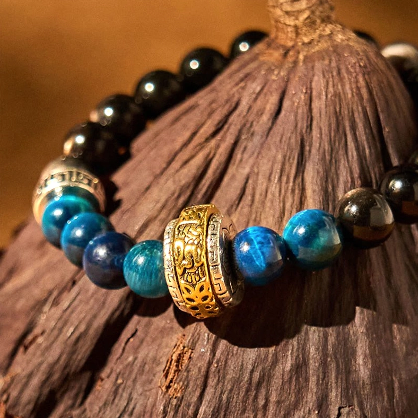 Close-up of Om Mani Padme Hum engraved copper charm on Buddhist protection bracelet against wood grain
