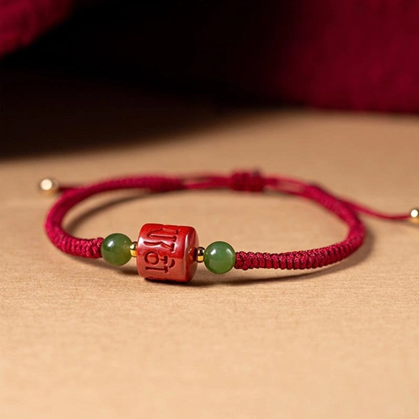 Complete view of Om Mani Padme Hum cinnabar braided rope bracelet with metal end caps and jade accents